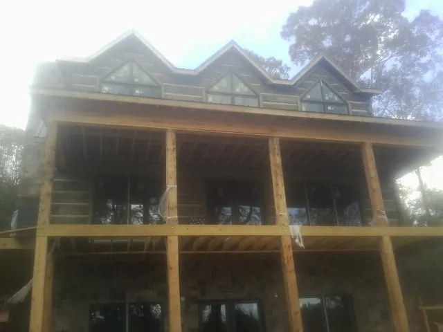 Dormers and porch framing on a large log home under construction — Roof Coating work by our crew in San Felipe