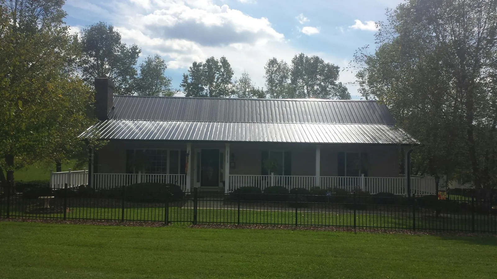Gray metal roof on a brick ranch with a full width front porch — Gutter Guard Installation work by our crew in San Felipe