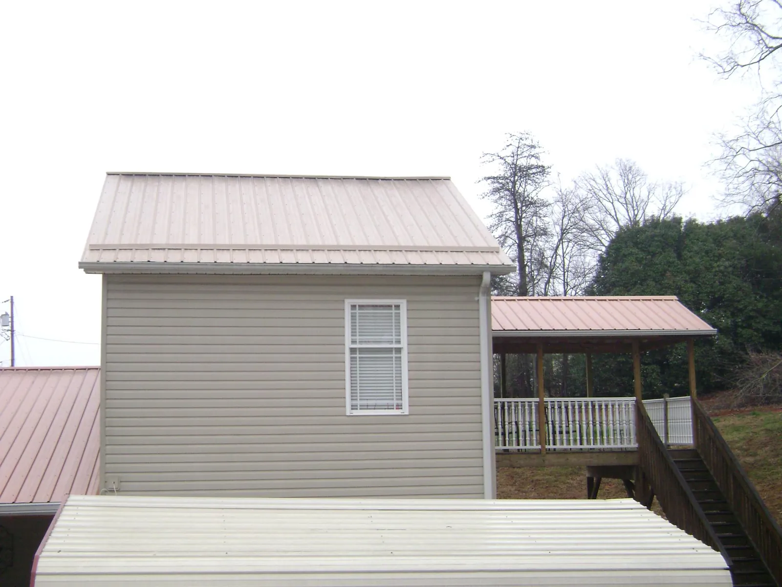 Tan metal roofs on a two story addition and attached porch, from a Roof Replacement job in San Felipe
