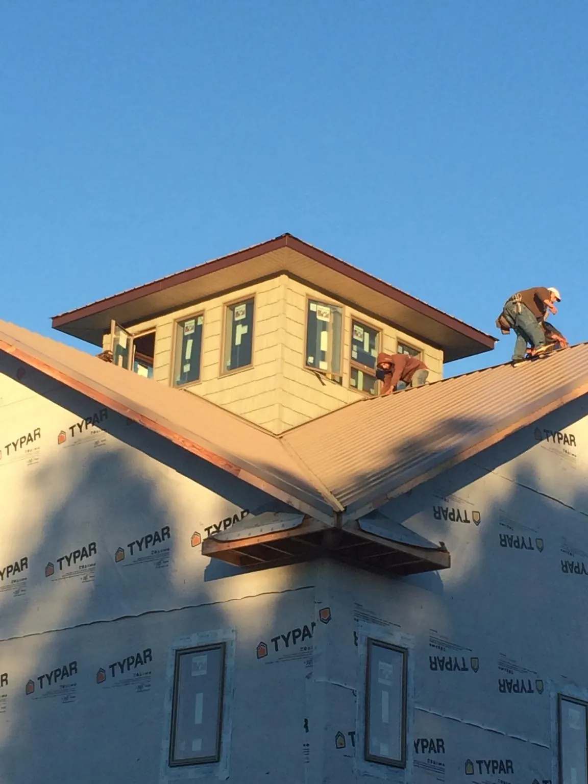 Roofers working around a rooftop cupola on a new metal roof at sunset — Roof Waterproofing in San Felipe by Roofing Brothers